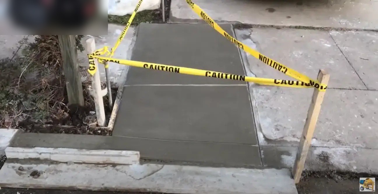 Freshly poured concrete walkway taped off while it cures